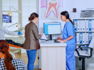 Patient checking in using Medi-EHR kiosk EHR system at clinic front desk.